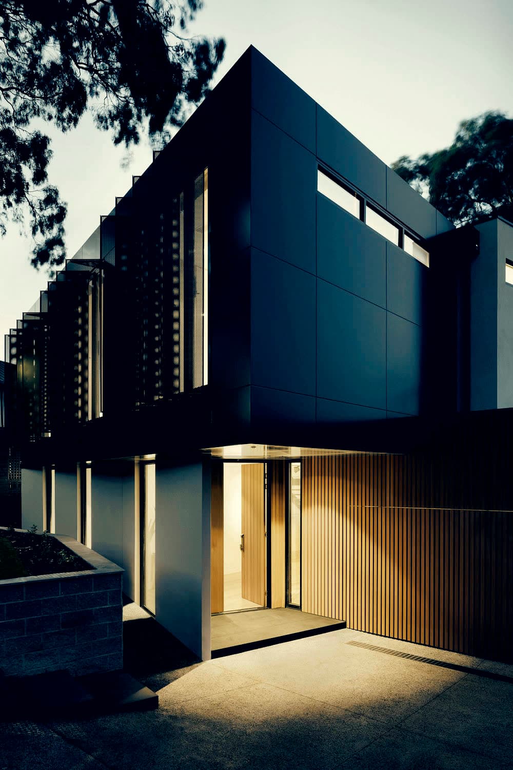 Dark-clad courtyard house with a lit entry