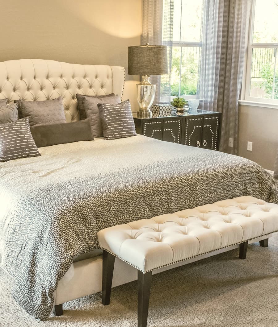 Principal bedroom with a tufted headboard and linen bench